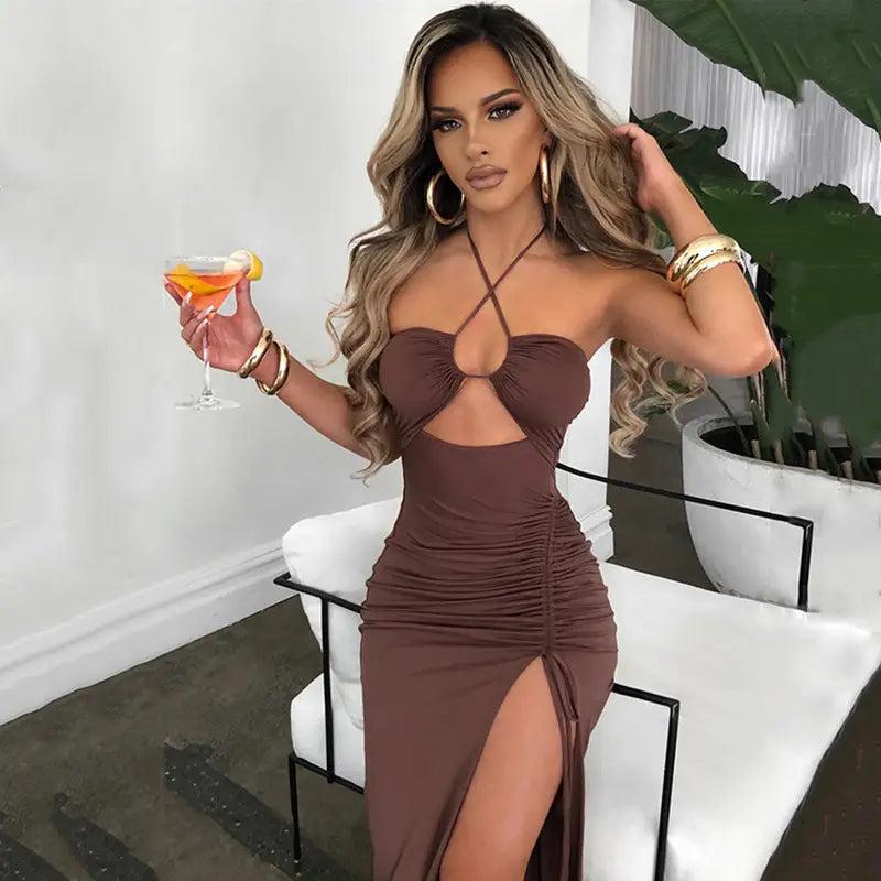 A stylish brown ruched halterneck satin split maxi dress with a strapless bodice, chest cutout detail, and a high slit.