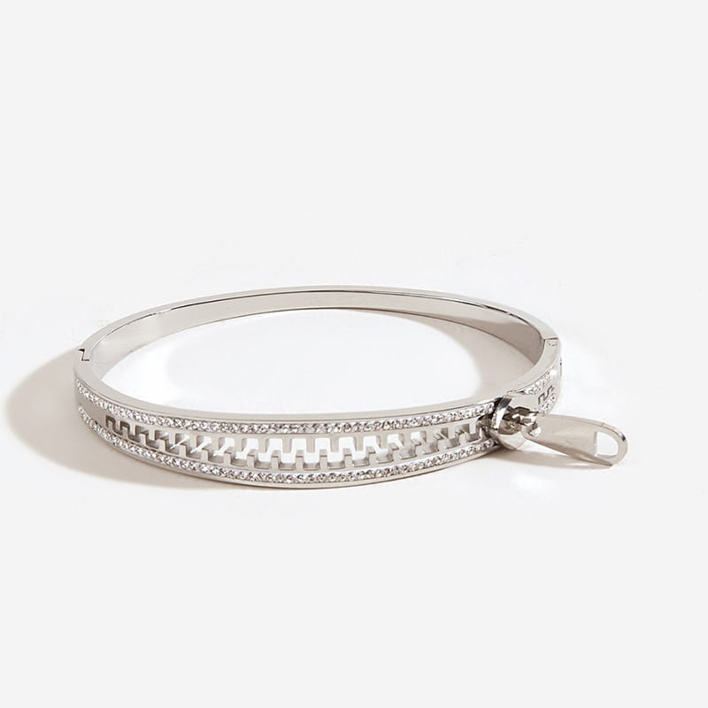 Silver bangle bracelet with zipper design and embedded crystals made of interlocking titanium steel.