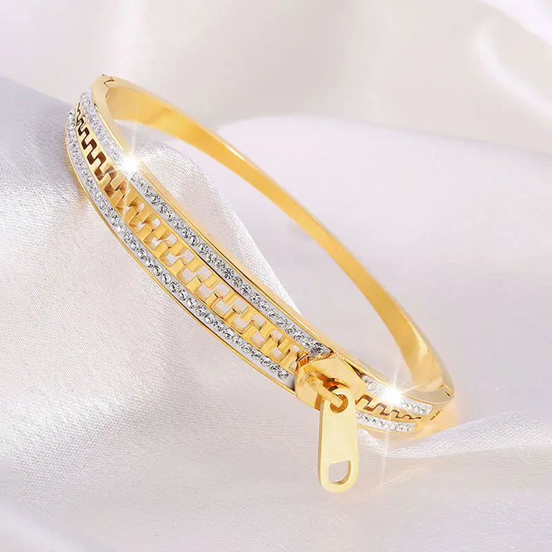Gold-toned crystal interlocking titanium steel zipper bangle bracelet featuring a sleek chain design adorned with rows of sparkling clear crystals.