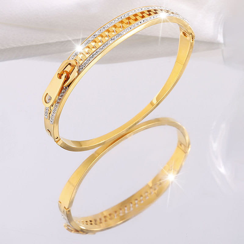 Gold-toned crystal interlocking titanium steel zipper bangle bracelet with textured chain design and embedded clear crystals along the top edge.