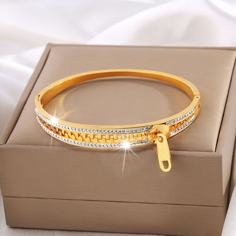 Gold-toned crystal interlocking titanium steel bangle bracelet featuring a zipper closure and two rows of clear rhinestones in an interlocking chain pattern.