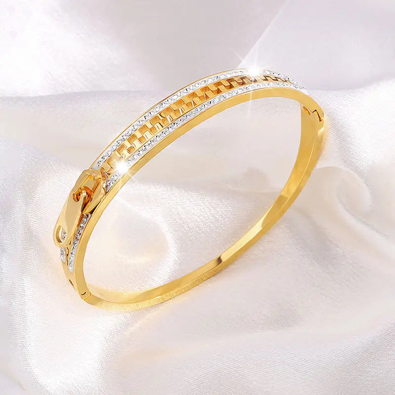 Gold-toned crystal interlocking titanium steel zipper bangle bracelet with a textured chain-link design and embedded clear crystals along its length.