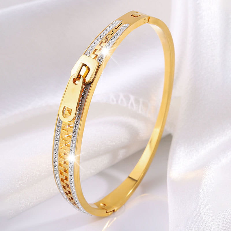 Gold-toned crystal interlocking titanium steel zipper bangle bracelet with clear crystals embedded along the chain pattern and clasp.