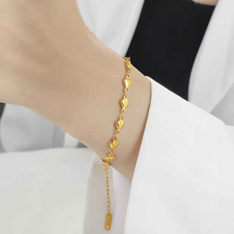 Polished gold heart link bracelet in titanium steel featuring a delicate chain and a small rectangular tag.