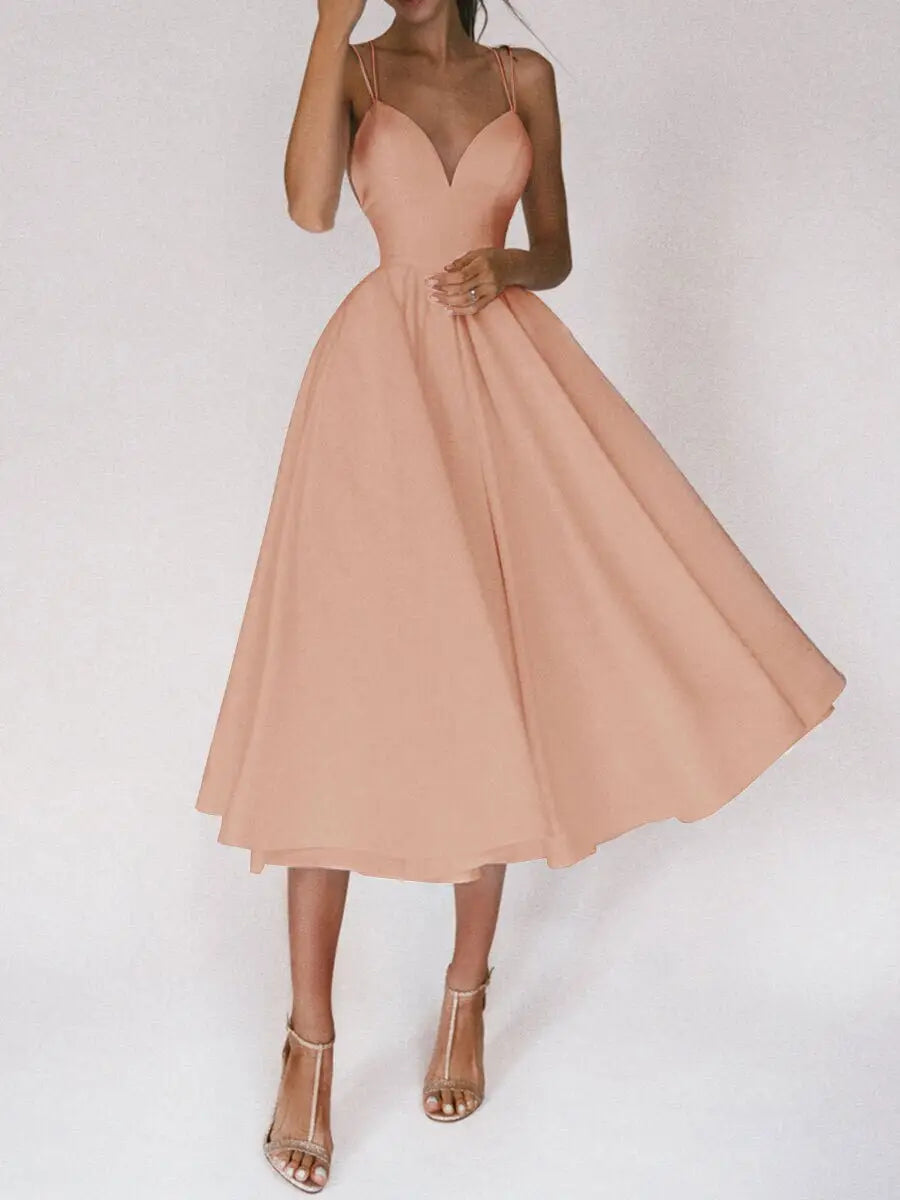 A flowing peach-colored satin v neck midi dress with a fitted bodice and delicate spaghetti straps.
