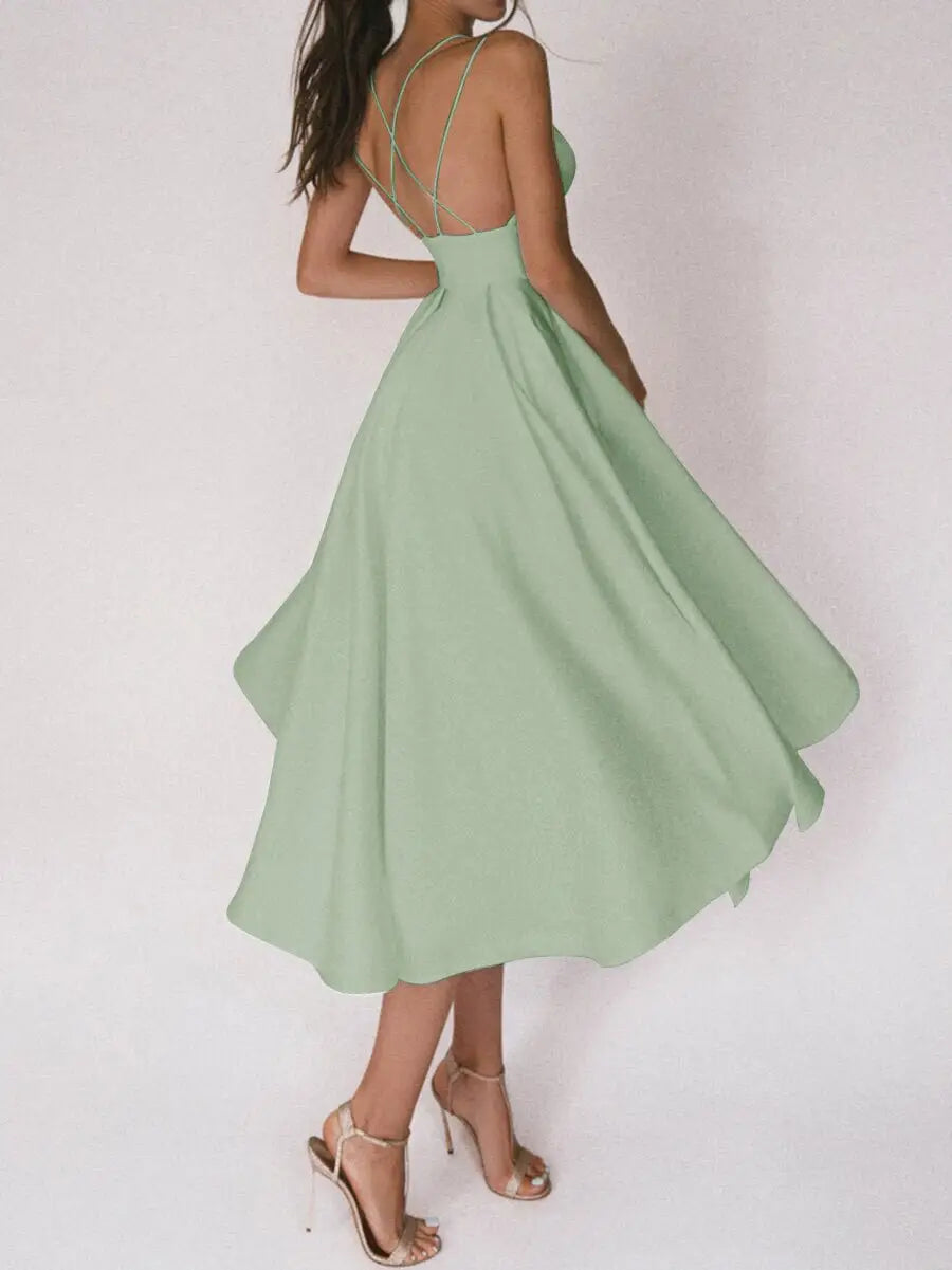 A flowing mint green satin v neck a line midi dress with a fitted bodice and crisscross back straps shown from the back.