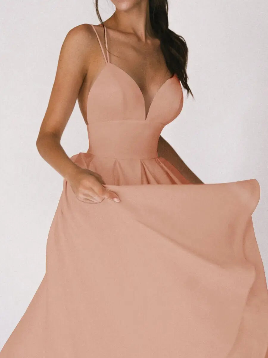 A soft blush pink satin v neck spaghetti strap a line midi dress with a fitted bodice and flowing skirt.