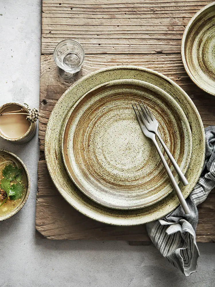 Stylish ceramic rustic speckled stoneware dinner plates with earthy green and beige glaze featuring concentric ring patterns.