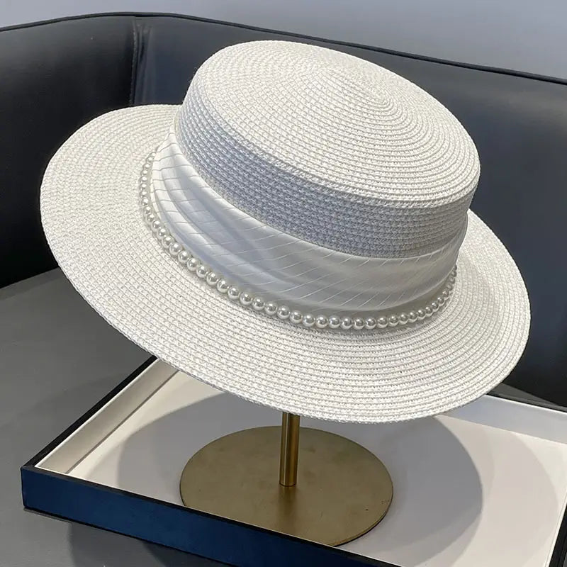 White woven straw sun hat for children with a wide brim and a decorative satin ribbon band adorned with pearls