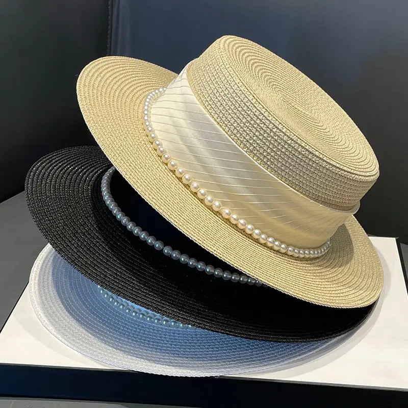 Beige straw boater sun hat for children featuring a cream satin ribbon and a row of pearls around the brim.