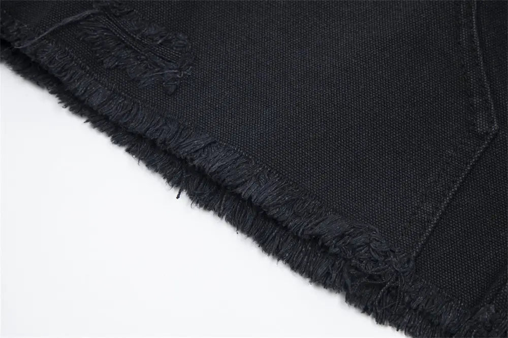 Pantalones cortos de mezclilla negros para hombre con dobladillo deshilachado desgastado, elaborados con una tela de mezclilla resistente.