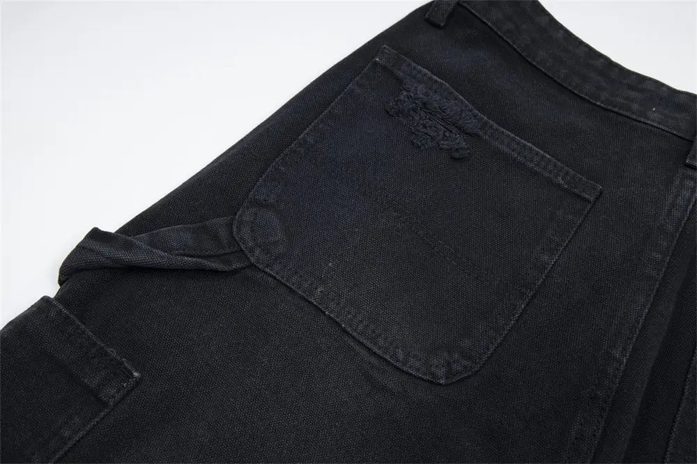 Pantalones cortos de mezclilla negros para hombre con parche desgastado en el bolsillo delantero y dobladillo deshilachado, elaborados con material de mezclilla.