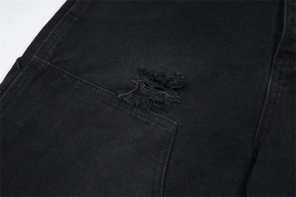 Pantalones cortos de mezclilla negros para hombre desgastados con dobladillo deshilachado, con una rasgadura deshilachada en el bolsillo delantero, elaborados con material de mezclilla resistente.