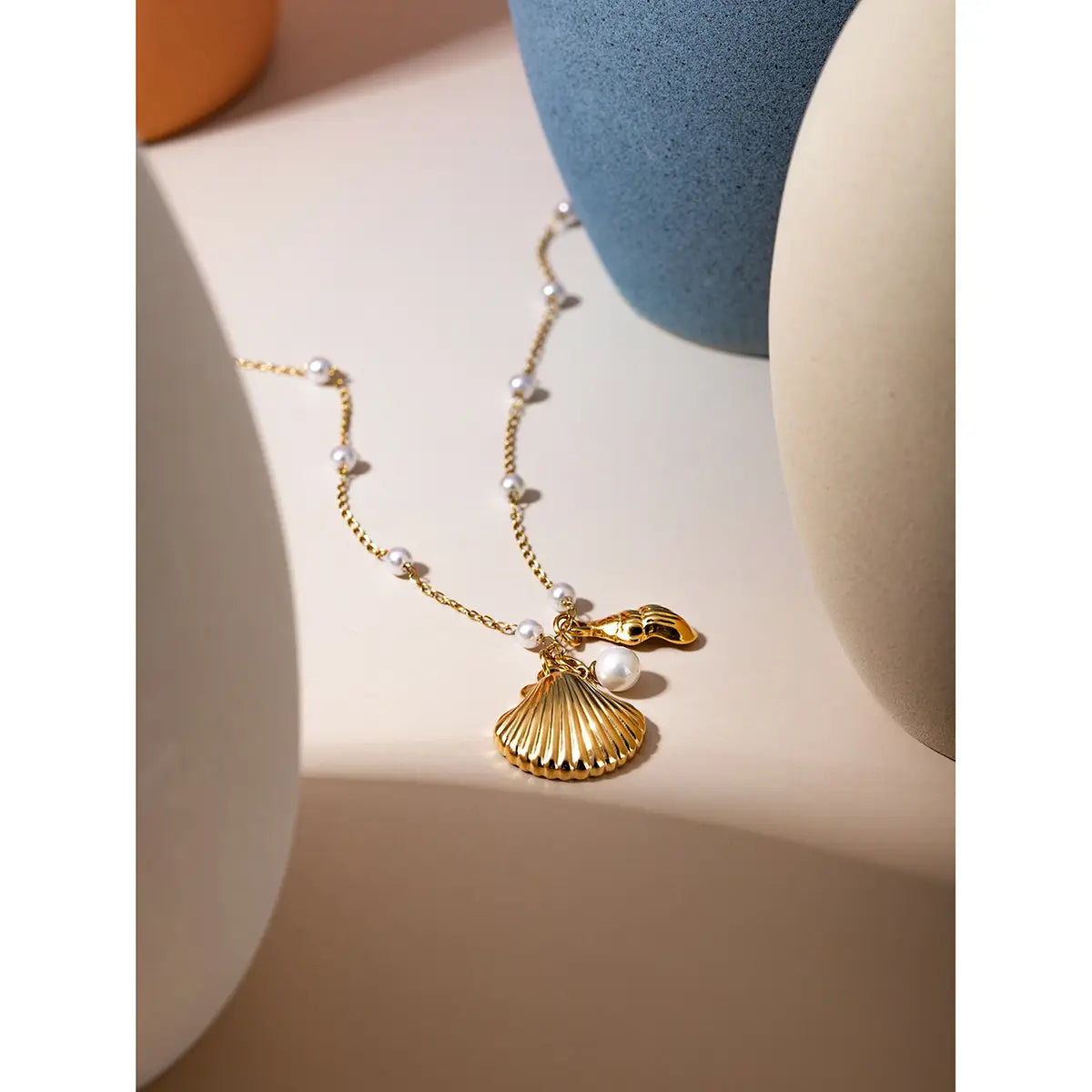 Gold-toned seashell pendant necklace with delicate chain and small pearls featured in an 18k gold plated pearl shell and starfish charm bracelet collection.