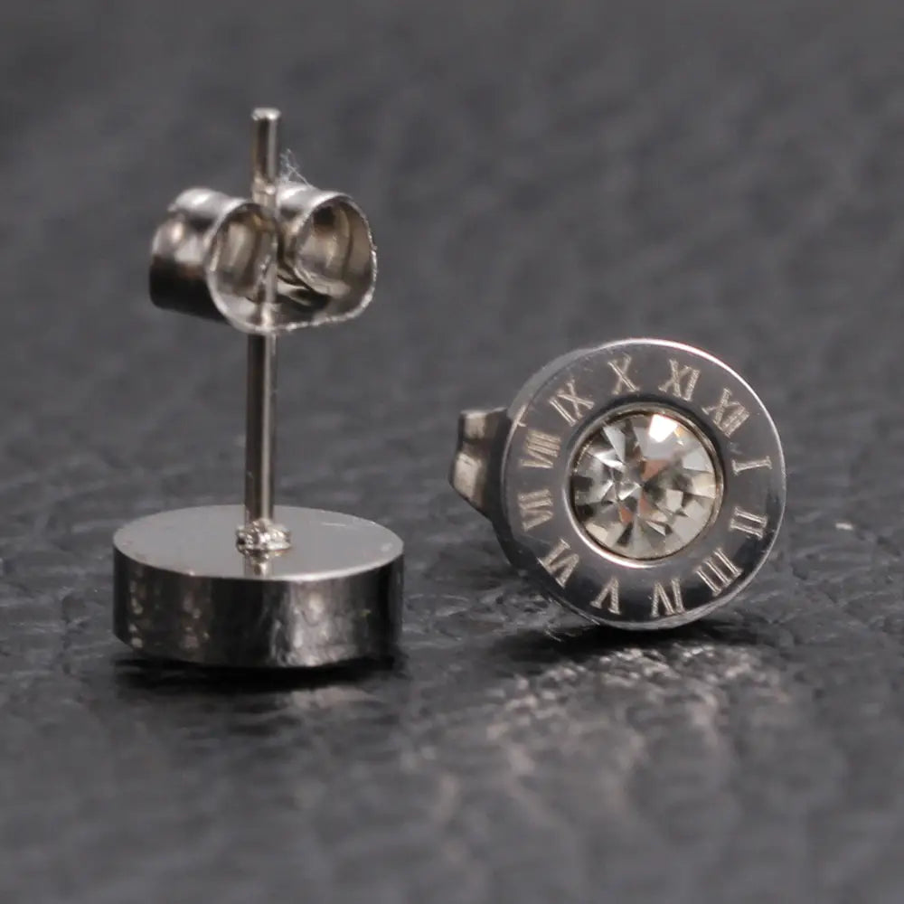 Boucles d’oreilles à tige en argent avec un motif circulaire de chiffres romains et un cristal transparent central présenté dans la parure de boucles d’oreilles à tige en diamant en or rose, motif de chiffres romains
