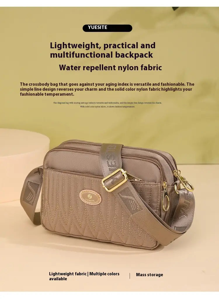 A taupe-colored quilted crossbody bag with gold hardware and strap made of lightweight water-repellent nylon fabric.
