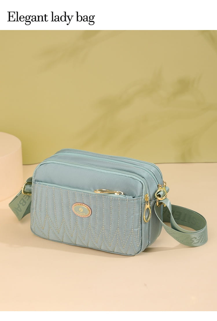 Light blue quilted crossbody bag with gold hardware and adjustable matching strap.