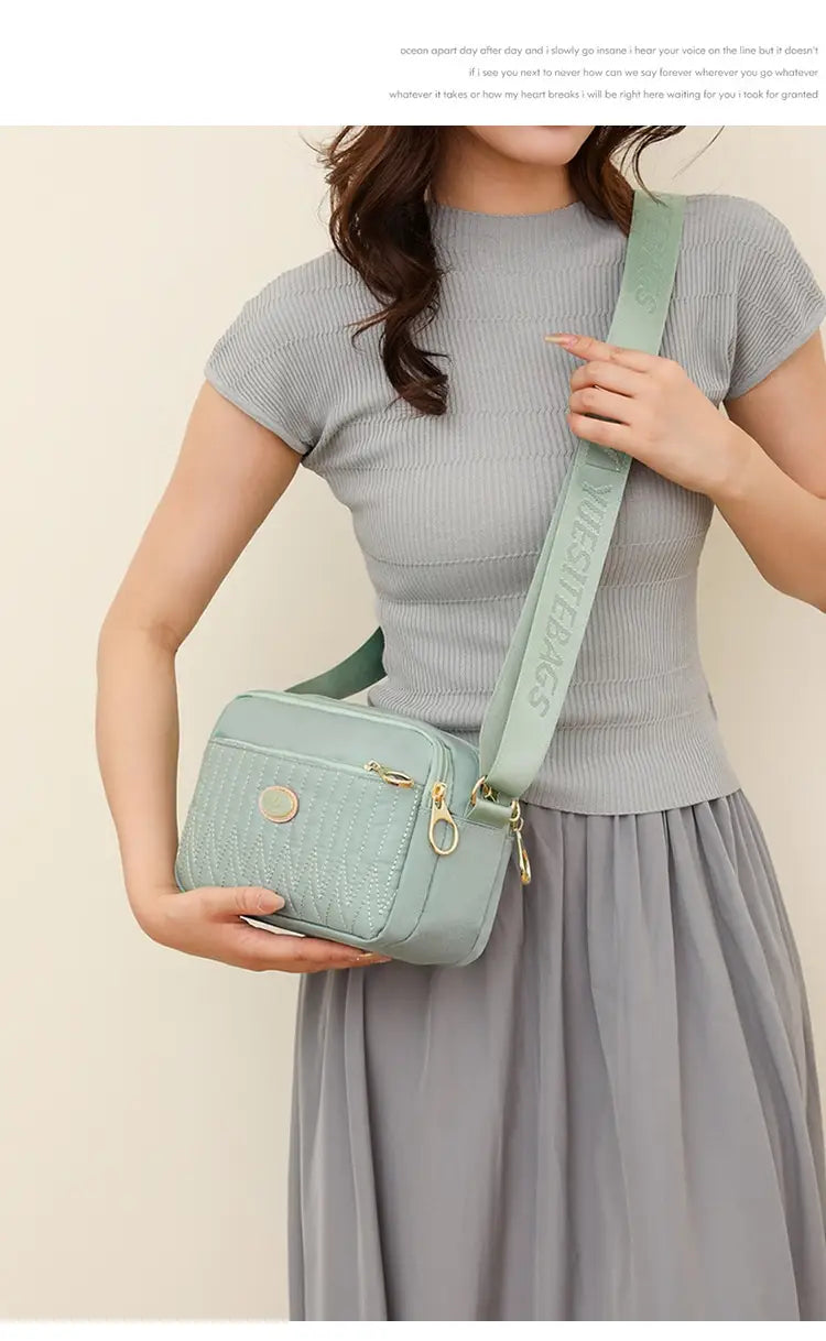 Light green quilted crossbody bag with textured surface and gold hardware and strap.