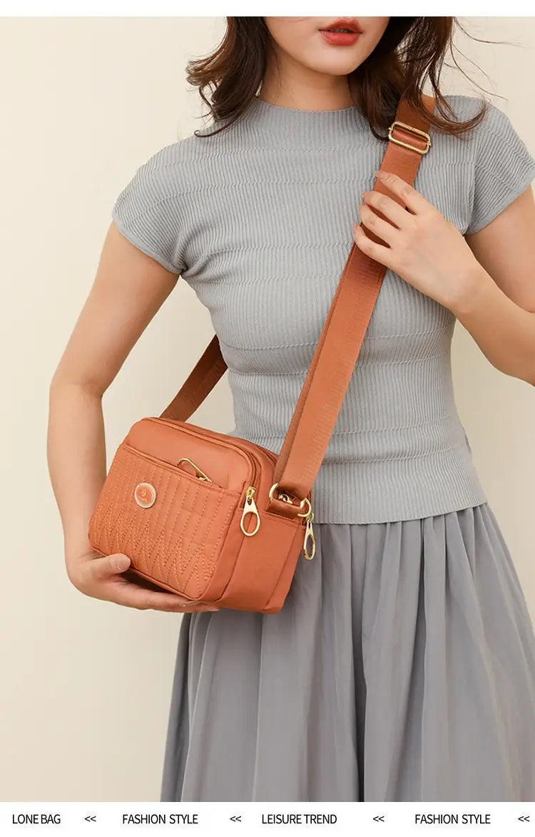 Tan quilted crossbody bag with gold-tone hardware and adjustable strap made of textured leather.