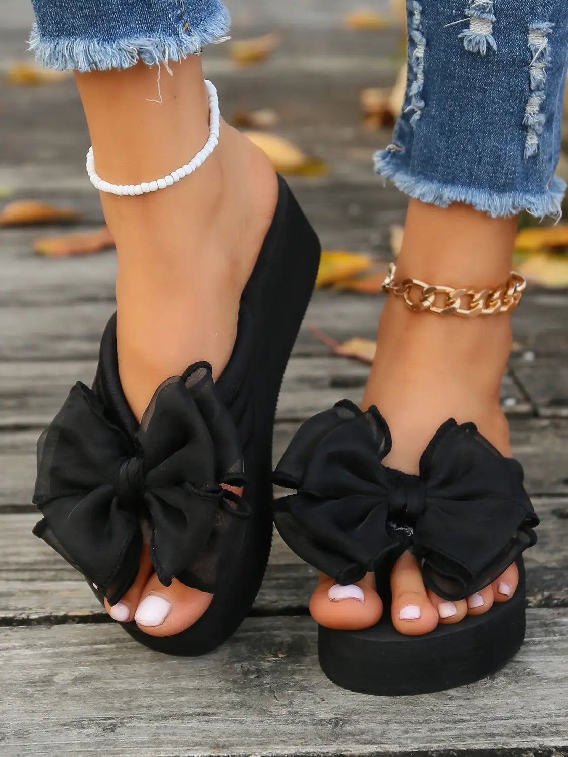 Sandalias tipo plataforma negras con grandes adornos de moño transparente fruncido en las correas superiores, diseñadas para un uso casual con estilo.