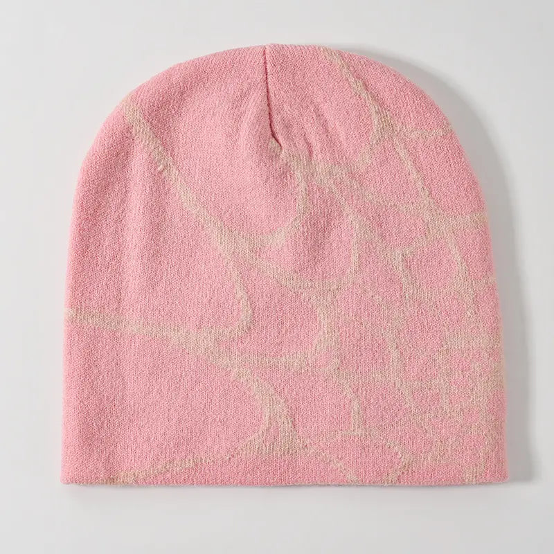 A soft pink spiderweb knit beanie winter hat featuring a subtle abstract pattern in lighter tones.