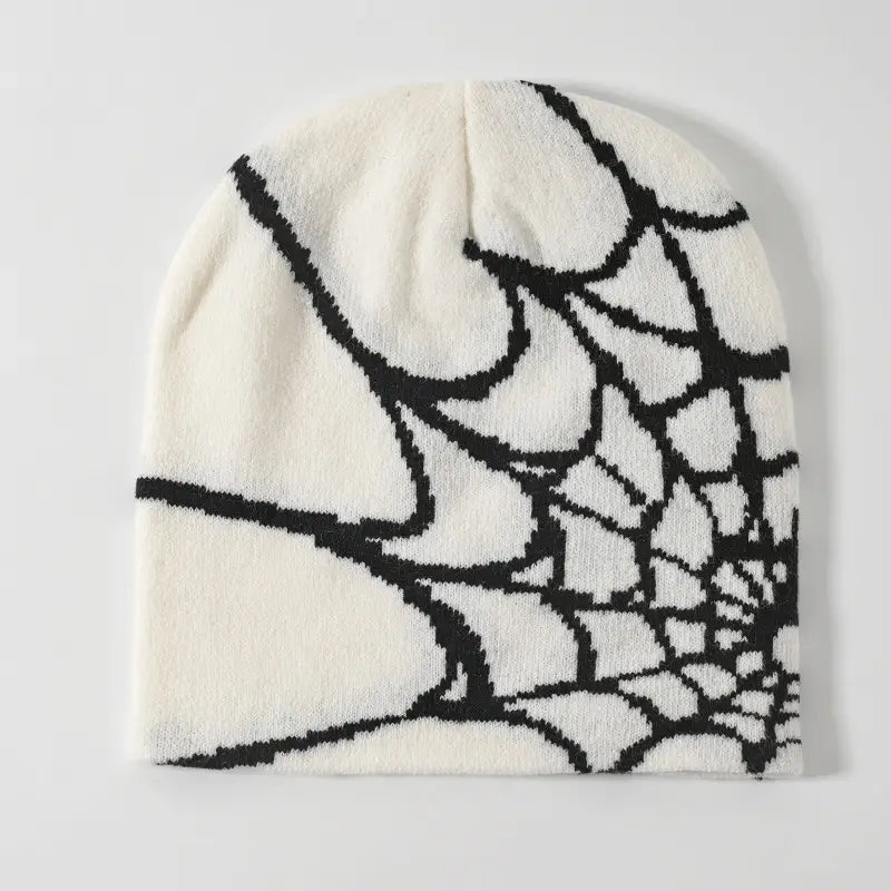 Cream-colored knit spiderweb knit beanie winter hat featuring a bold black spiderweb pattern.