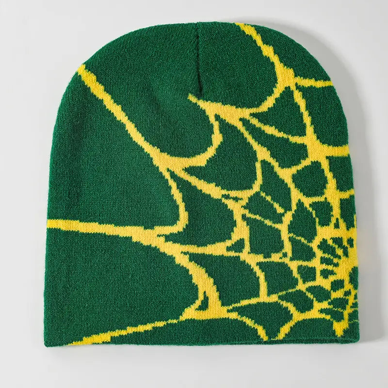 Green knit beanie winter hat featuring a bold yellow spiderweb pattern designed for cold weather use.