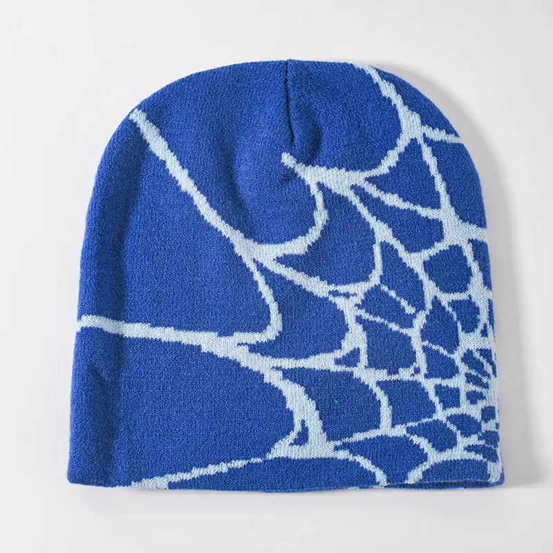 Blue knit beanie with a white spiderweb pattern designed as a winter hat for cold weather.