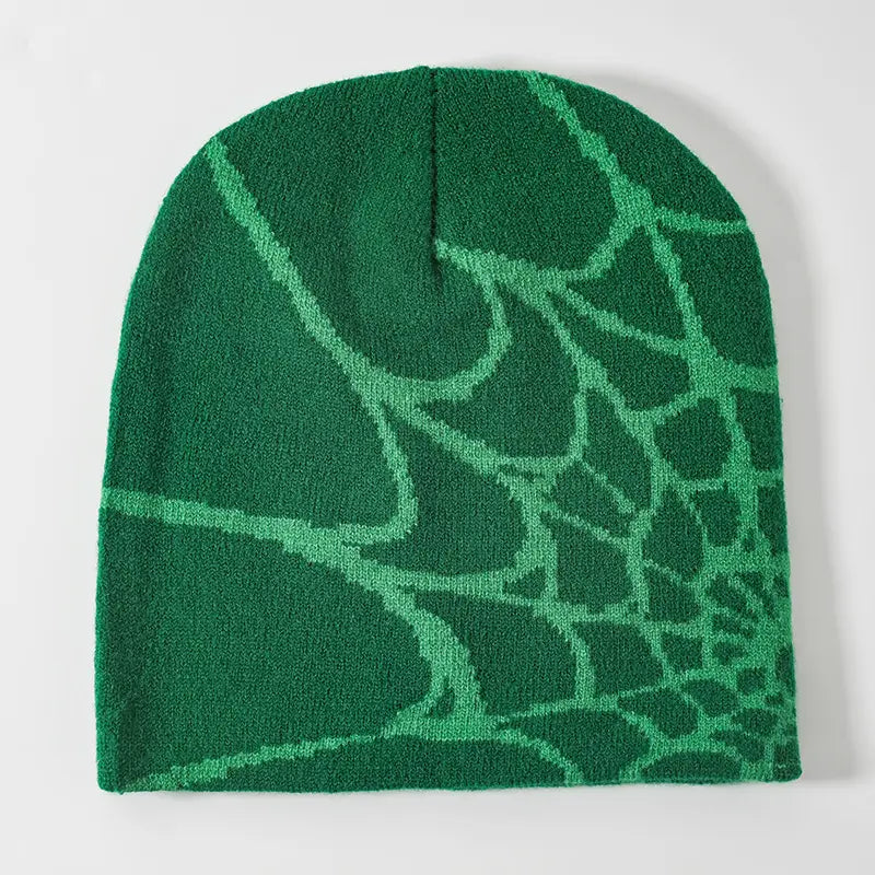 A knitted green beanie with a lighter green spiderweb pattern designed as a winter hat.