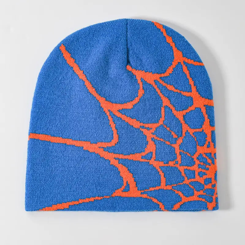 Blue knit beanie with a bold orange spiderweb pattern designed as a winter hat.
