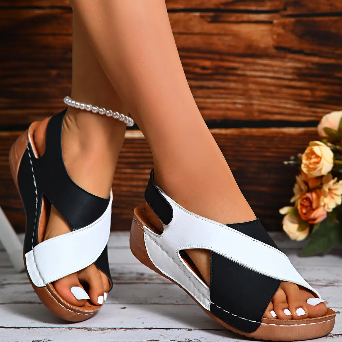 Sandalias tipo cuña con tiras cruzadas en negro y blanco con diseño a contraste de colores y suela marrón para un calzado de plataforma con estilo.