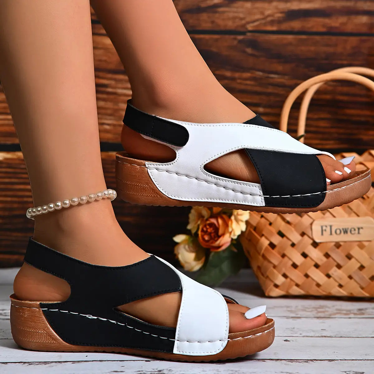 sandalias tipo cuña en negro y blanco con plataforma a contraste de colores y tiras cruzadas en la plataforma sobre suela de madera, mostradas desde el lado posterior