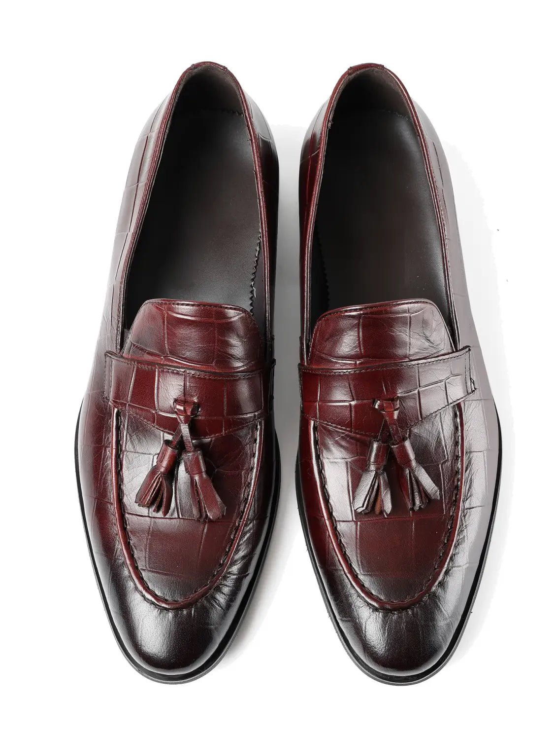 Mocasines con borlas de cuero con estampado de cocodrilo color burdeos que muestran los detalles del diseño frontal y lateral.