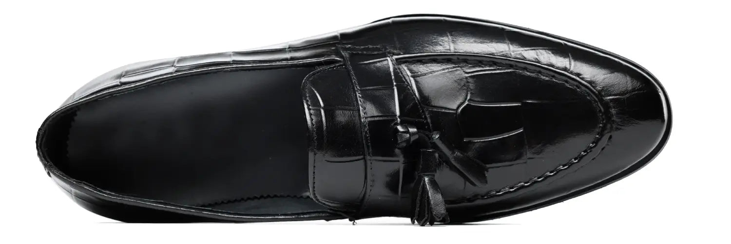 Mocasín de cuero con estampado de cocodrilo negro con detalle de borla, destacado en los mocasines con borlas de cuero con estampado de cocodrilo color burdeos.