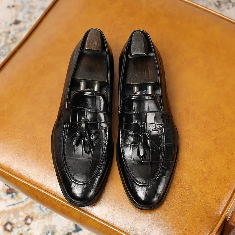 Mocasines de cuero con estampado de cocodrilo negro con detalles de borla y un acabado burdeos elegante, ideales para vestimenta formal.