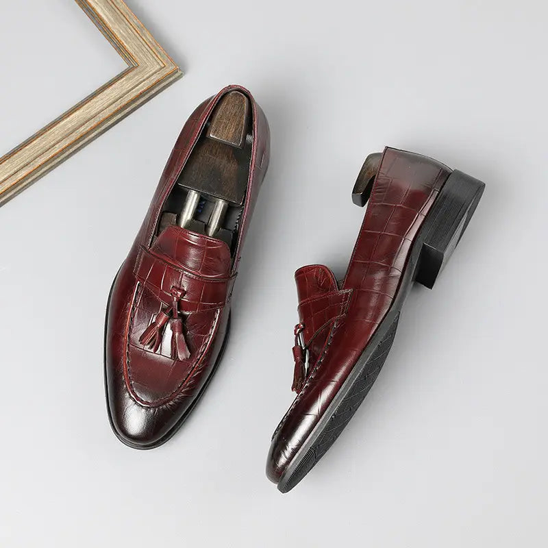 Mocasines con borlas de cuero con estampado de cocodrilo color burdeos con acabado pulido y suelas negras de goma.