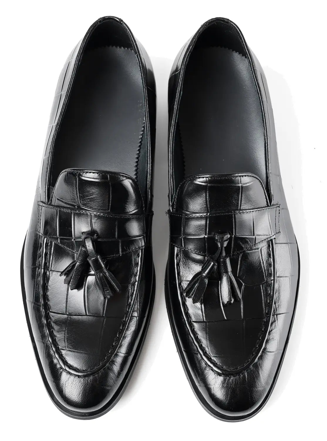 Mocasines de cuero con estampado de cocodrilo negro con borlas, mostrados desde la parte trasera