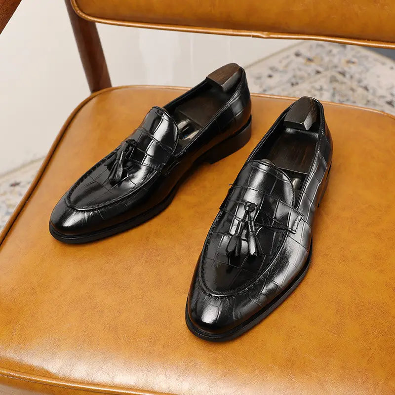 Mocasines de cuero con estampado de cocodrilo negro con borlas que muestran un diseño elegante y sofisticado.