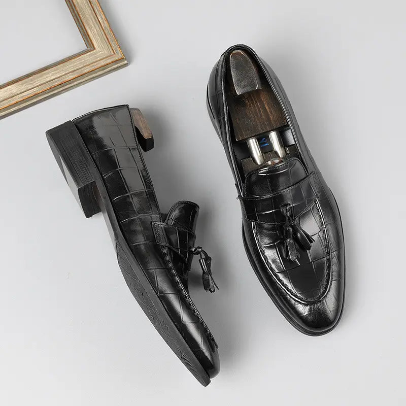 Mocasines de cuero con estampado de cocodrilo negro con borlas que muestran una textura detallada y un diseño elegante