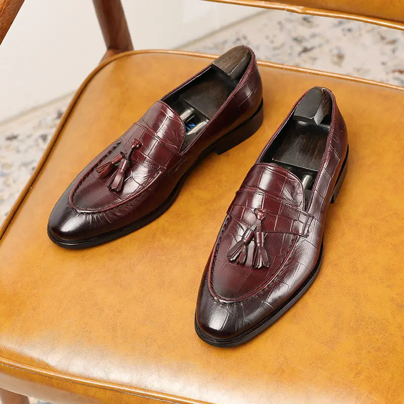 Mocasines con borlas de cuero con estampado de cocodrilo color burdeos que muestran una textura sofisticada y un color intenso.