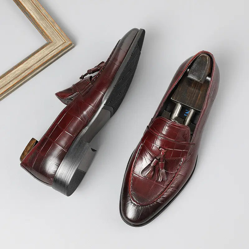 Mocasines con borlas de cuero con estampado de cocodrilo color burdeos que muestran una rica textura y un diseño elegante.
