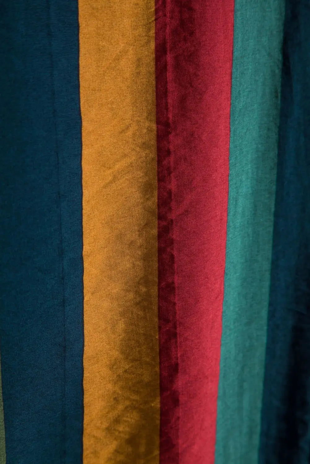 A striped short sleeve button up shirt featuring vibrant vertical stripes in deep blue mustard yellow rich red and teal green fabric.