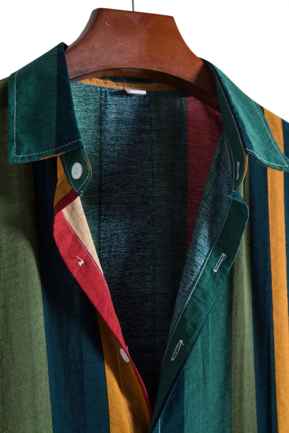 A vibrant striped short sleeve button up shirt featuring vertical green red and mustard yellow stripes with a patchwork collar.