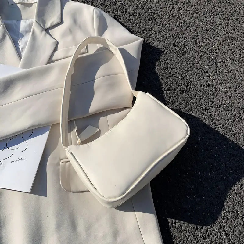 Cream-colored faux leather underarm shoulder bag with a minimalist design and structured rectangular shape.