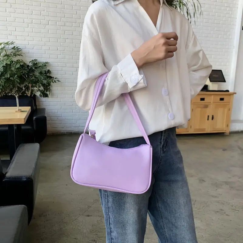 A soft lavender-colored underarm shoulder bag made of faux leather with a sleek rectangular design and smooth material.