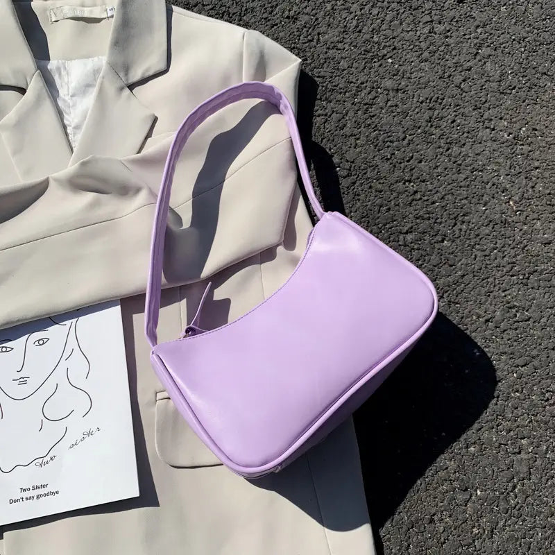 A sleek lavender underarm shoulder bag with a smooth glossy finish and a curved minimalist design made of faux leather rectangular purse.