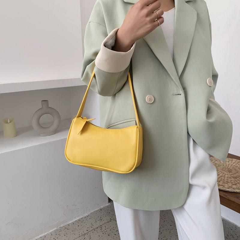 Bright yellow leather underarm shoulder bag with a curved minimalist design made of faux leather and rectangular shape.