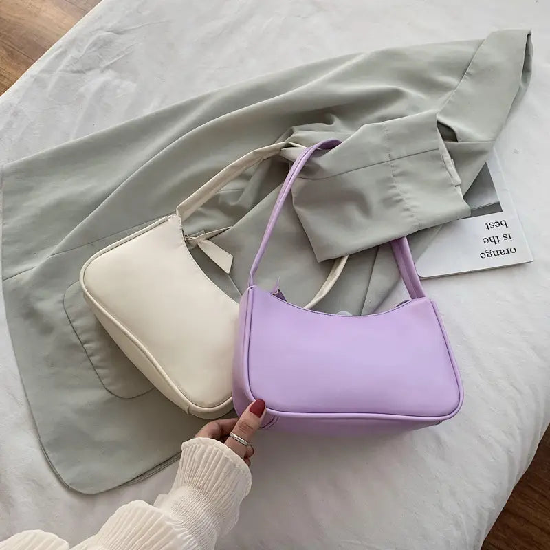 A soft lavender-colored underarm shoulder bag made of smooth faux leather with a structured rectangular shape and matching strap.