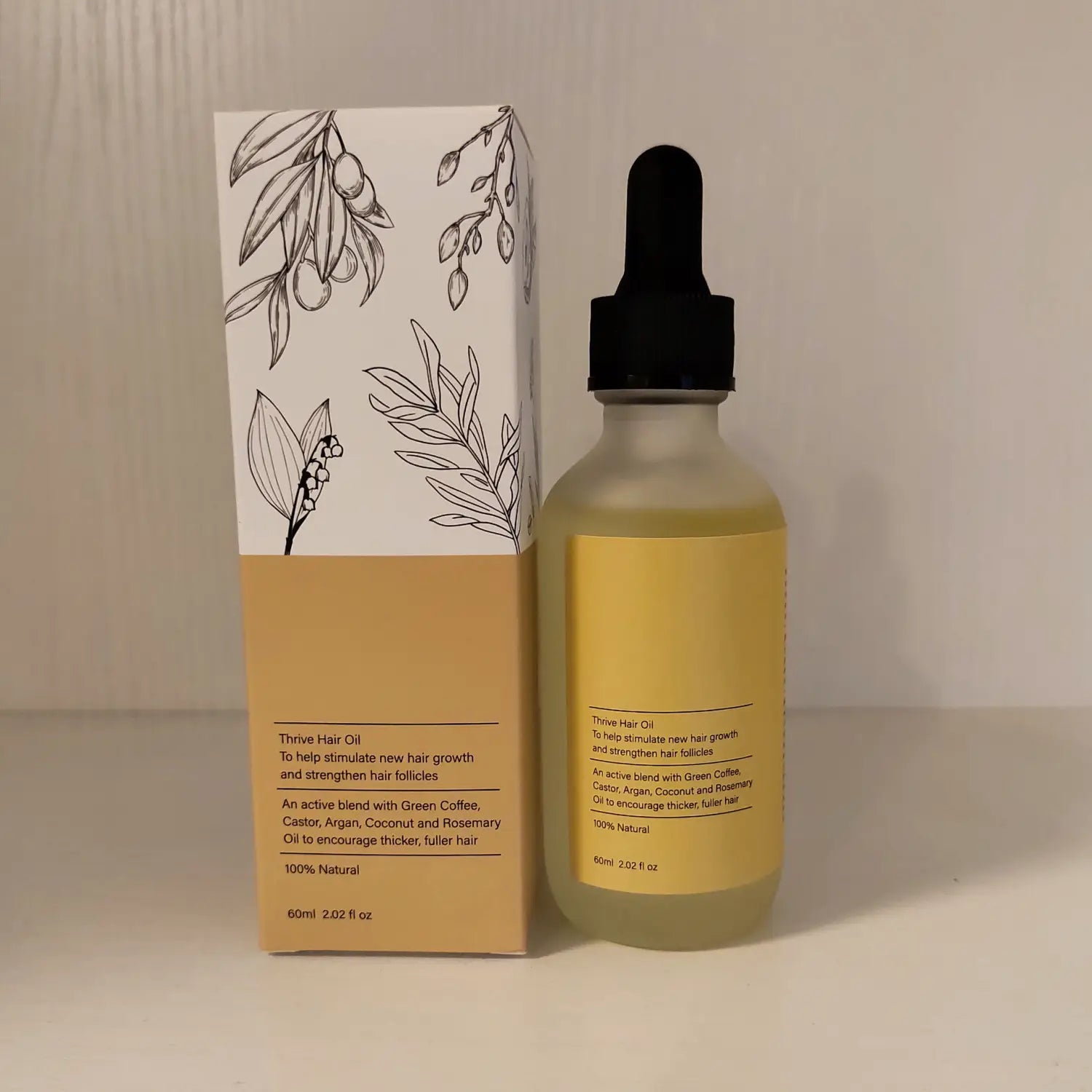 A clear glass bottle with a black dropper cap contains golden-yellow thrive hair growth oil moisturizing repair serum 60ml packaged in an olive-toned box with botanical line drawings.