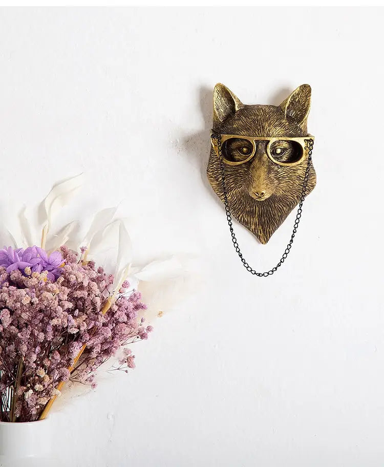 Antique brass fox head wall decor with gold-rimmed glasses and a black chain hanging from its neck made of brass resin figurines.